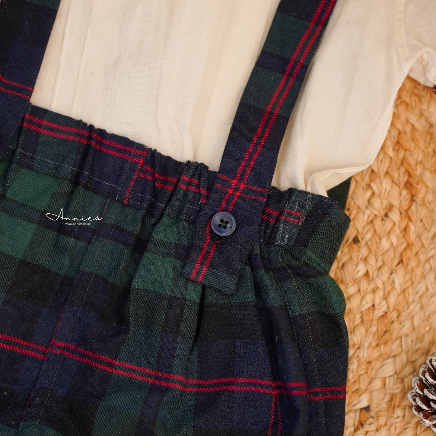 Plaid dress with suspenders on a woven surface