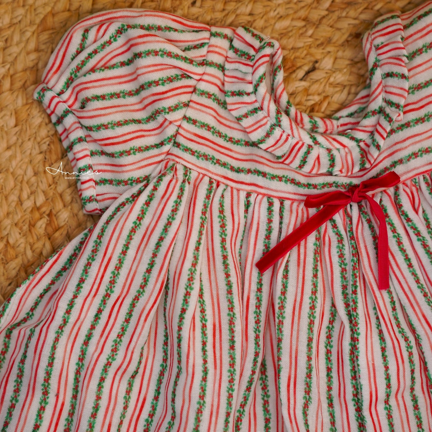 Red and green striped dress with a red ribbon on a woven surface