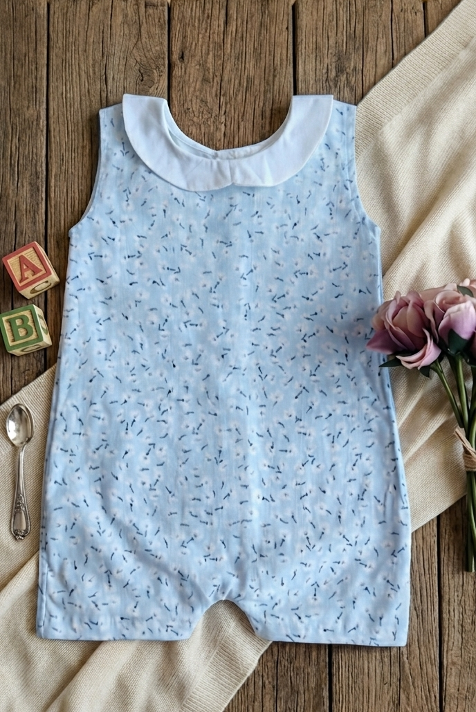Light blue sleeveless dress with white collar on a wooden surface with flowers and toys.