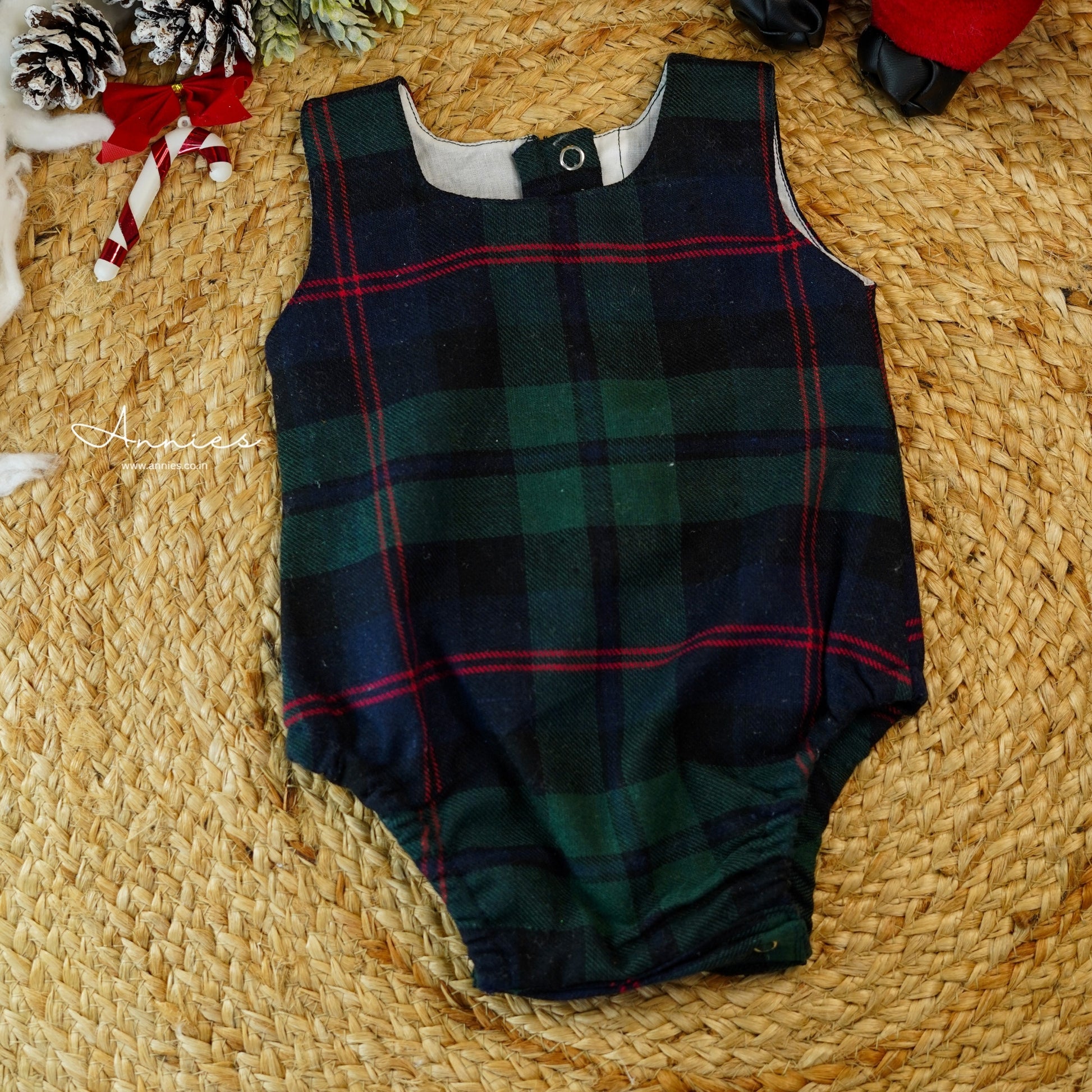 Green plaid baby romper on a woven surface