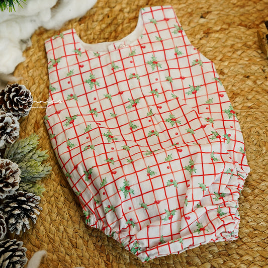 Baby romper with red and green pattern on a woven surface