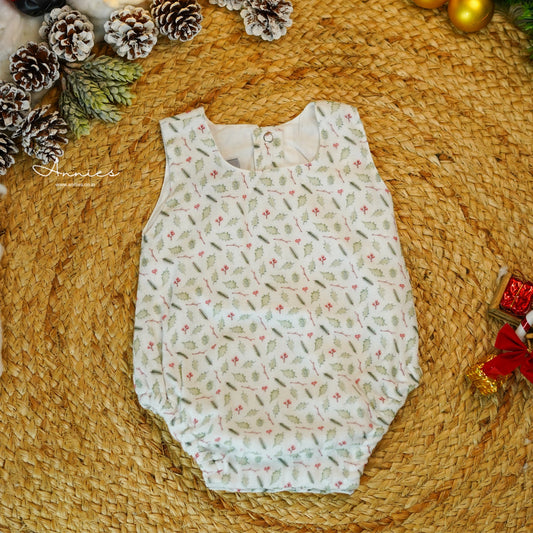 Baby romper with floral pattern on a woven surface with pinecones and a red bow.