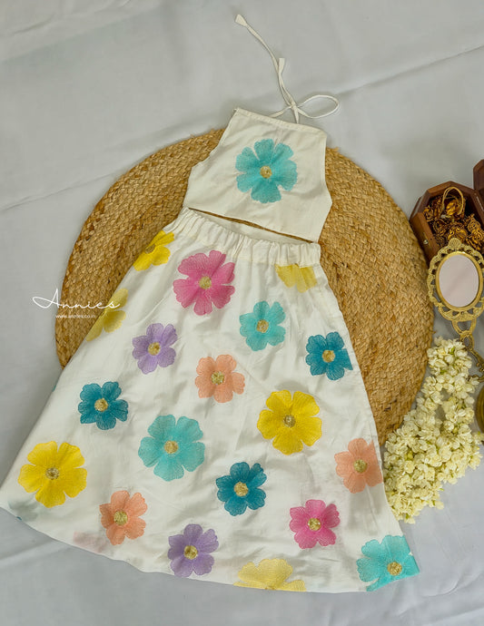 White dress with colorful floral patterns on a textured surface for girls by annies.co.in