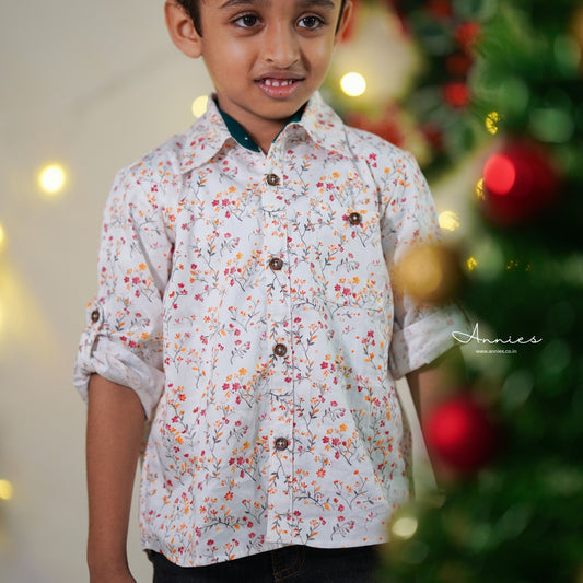 Child wearing a floral shirt with a blurred Christmas tree in the background