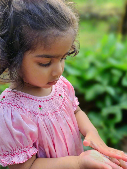Girl wearing bishop smocked dress by Annies