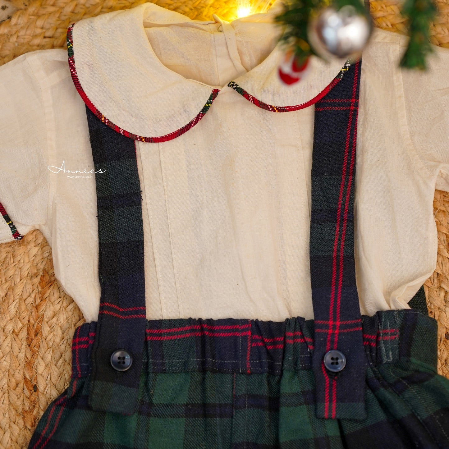 Children's outfit with white shirt and plaid skirt on a mannequin against a woven basket background.