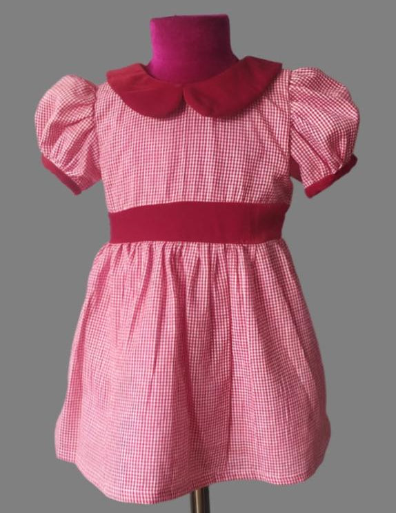A vintage-style girls' dress with handloom red plaid fabric, featuring a Peter pan collar and a waist belt, displayed on a mannequin.