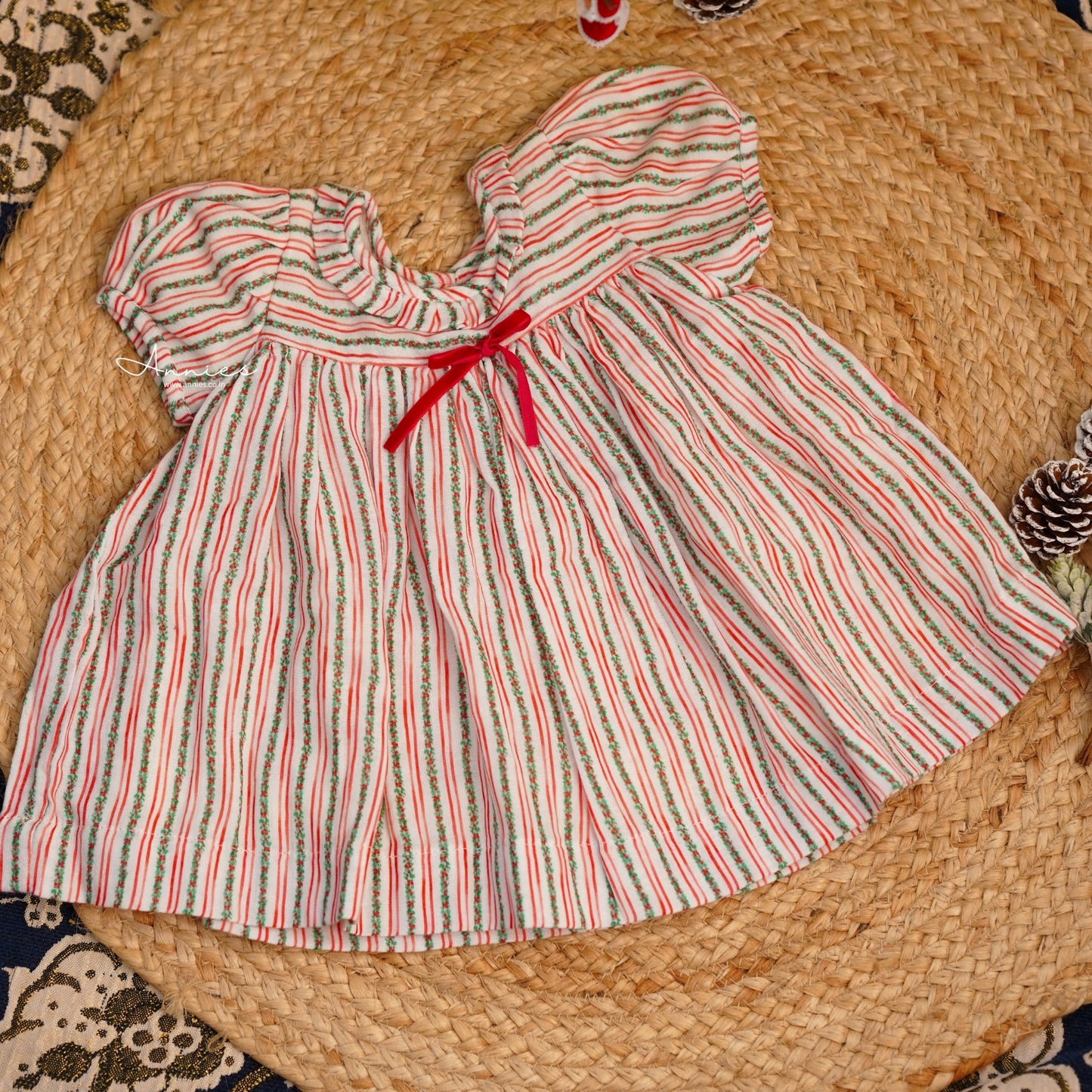 Striped dress with a red ribbon on a woven surface
