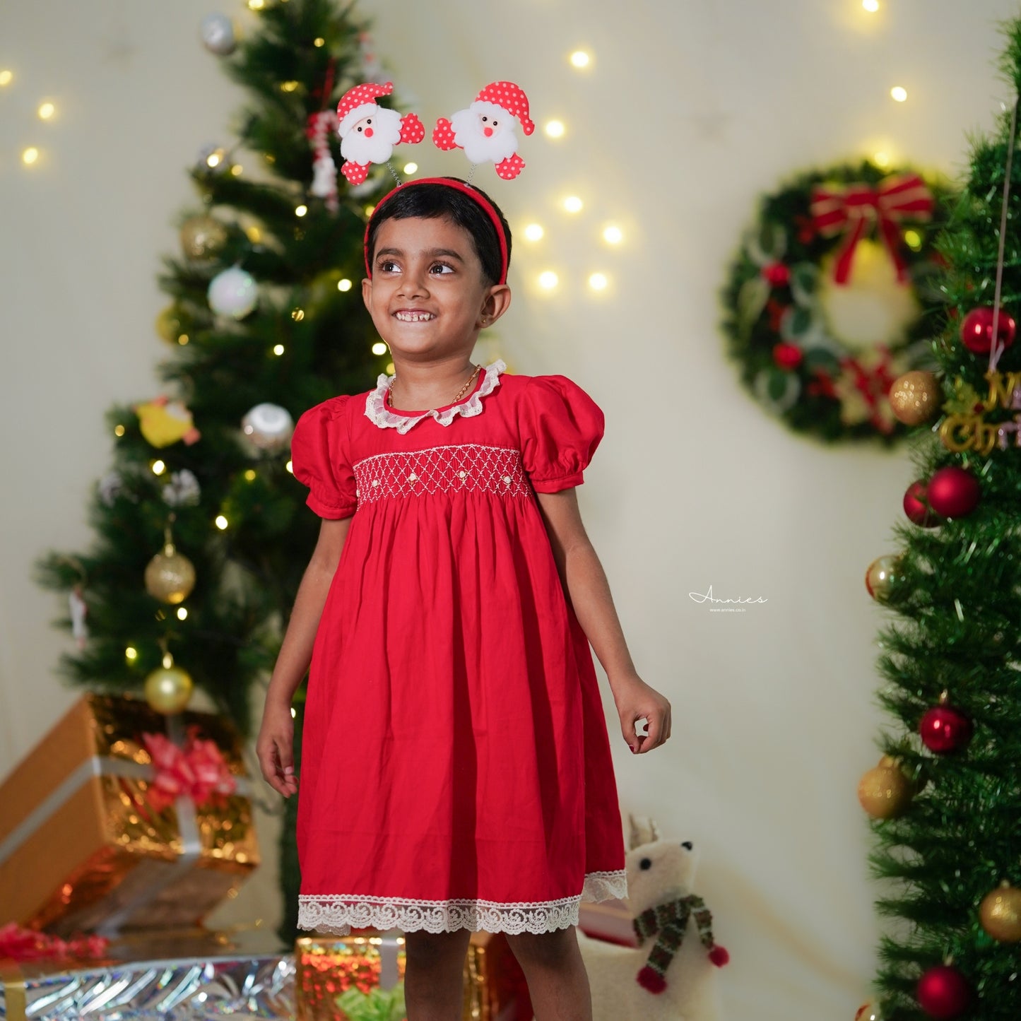 Child in a red dress with Christmas decorations in the background