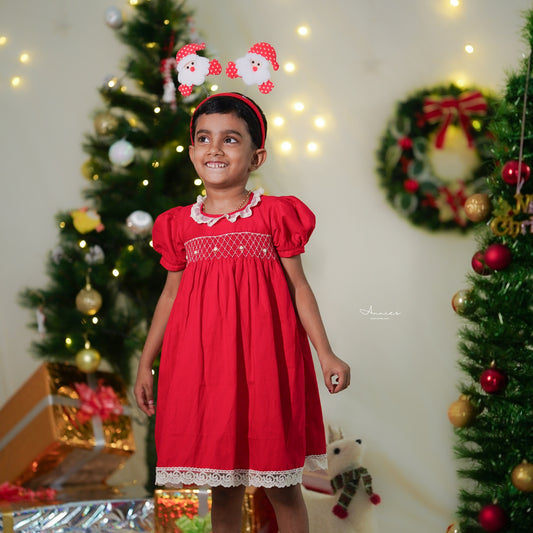 Child in a red dress with Christmas decorations in the background