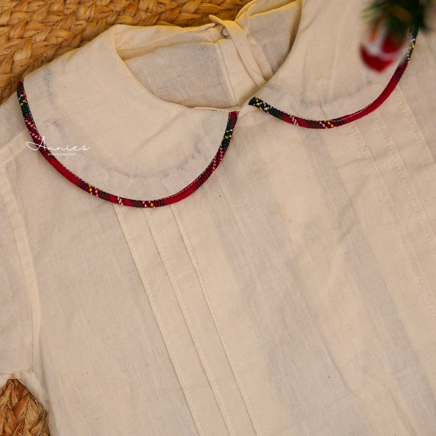 Close-up of a white shirt with a red beaded necklace on a textured surface