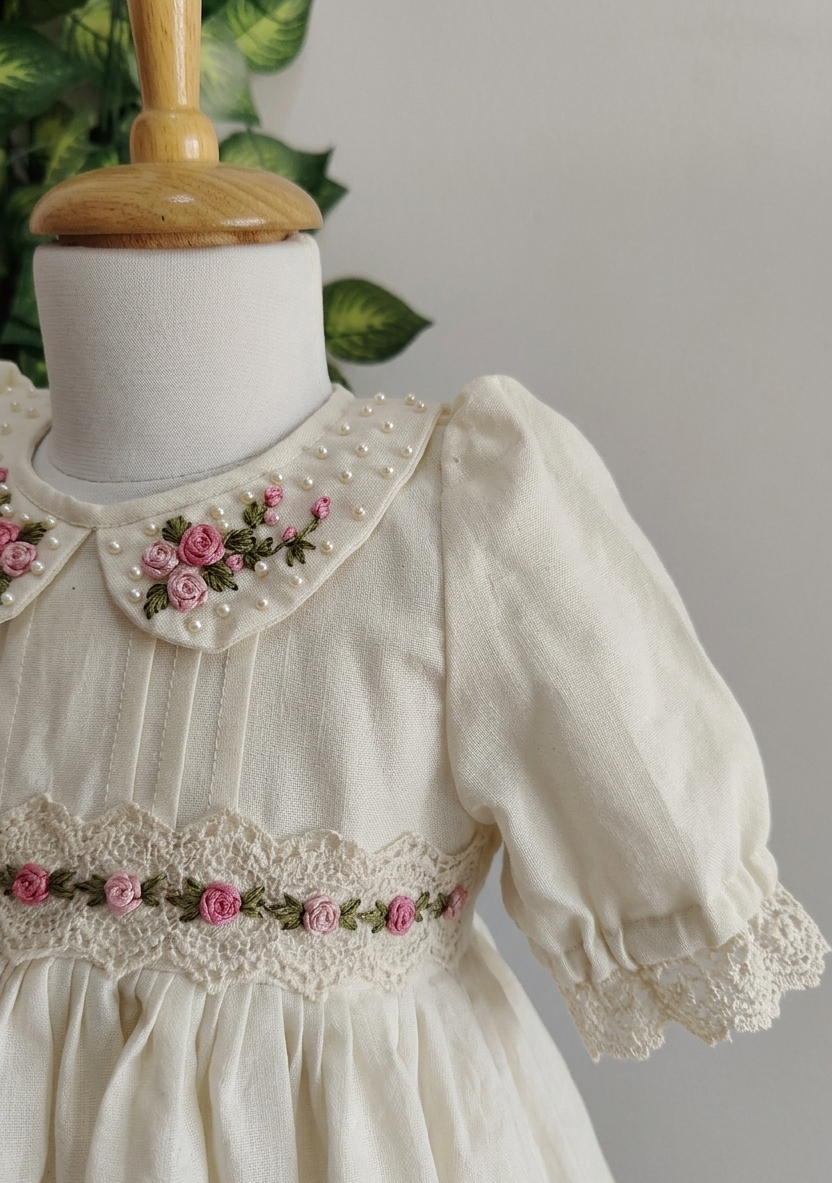 White dress with floral embroidery on a mannequin against a gray background