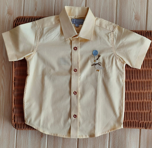 Beige shirt with embroidery on a woven basket against a wooden background